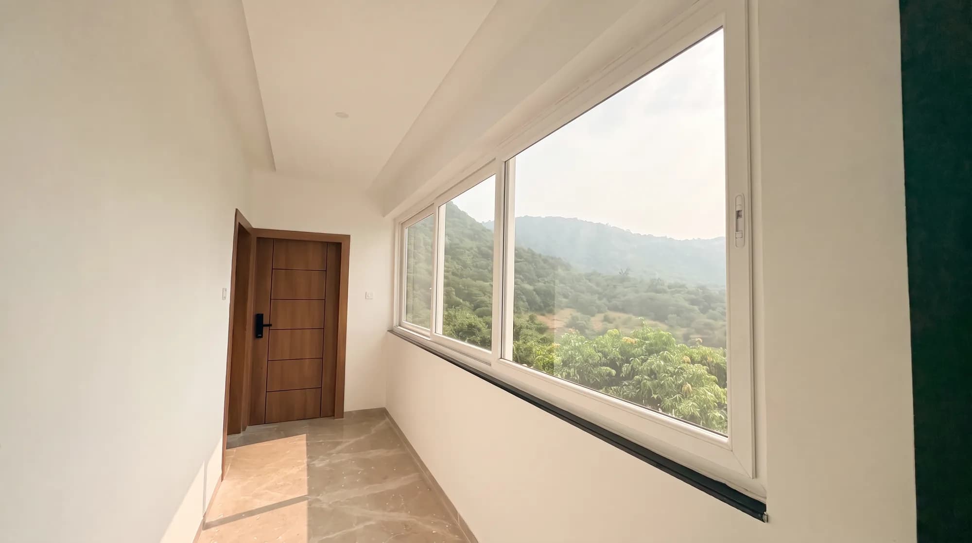 A bright corridor with a large window framing a wooded valley