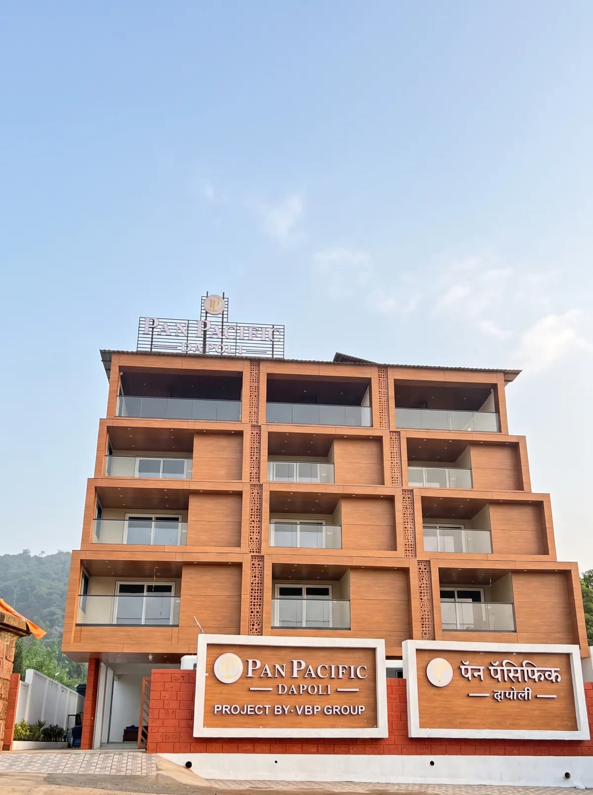Pan Pacific Dapoli seen from the street, with its terracotta façade and signboards