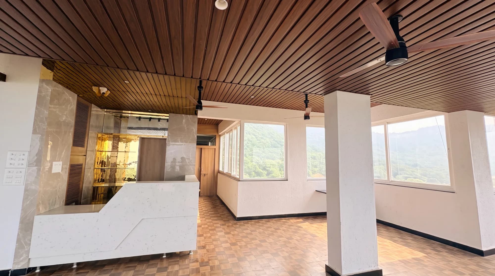 The reception counter, marble wall and wooden ceiling, with hill views through the windows